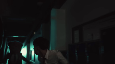 a man in a white shirt and tie walking down a hallway