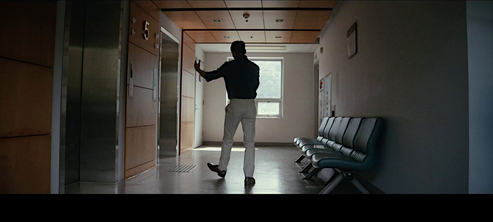 a man standing in a hallway next to a chair