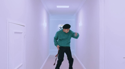 a man in a green sweater is walking down a hallway