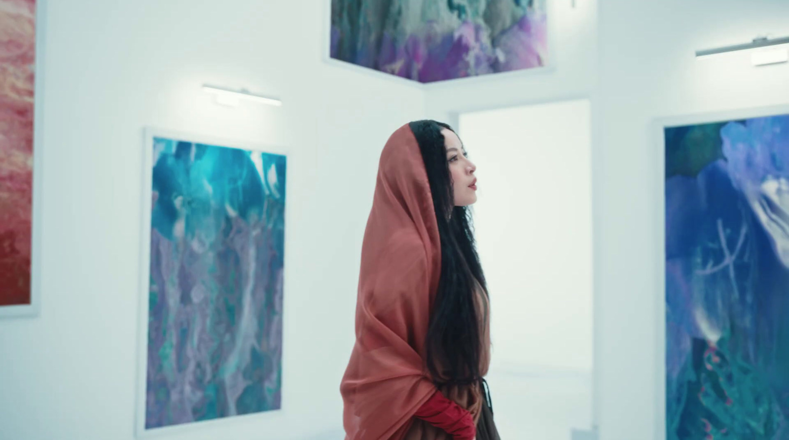 a woman standing in front of paintings in a room