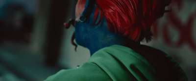 a man with red and blue hair and a green shirt