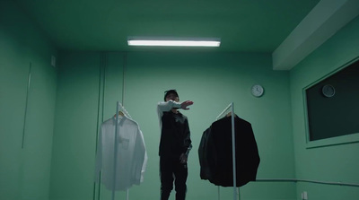 a man standing in a green room next to a coat rack