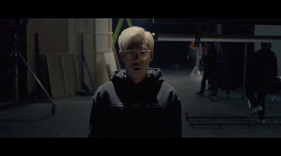 a man with white hair and glasses in a dark room