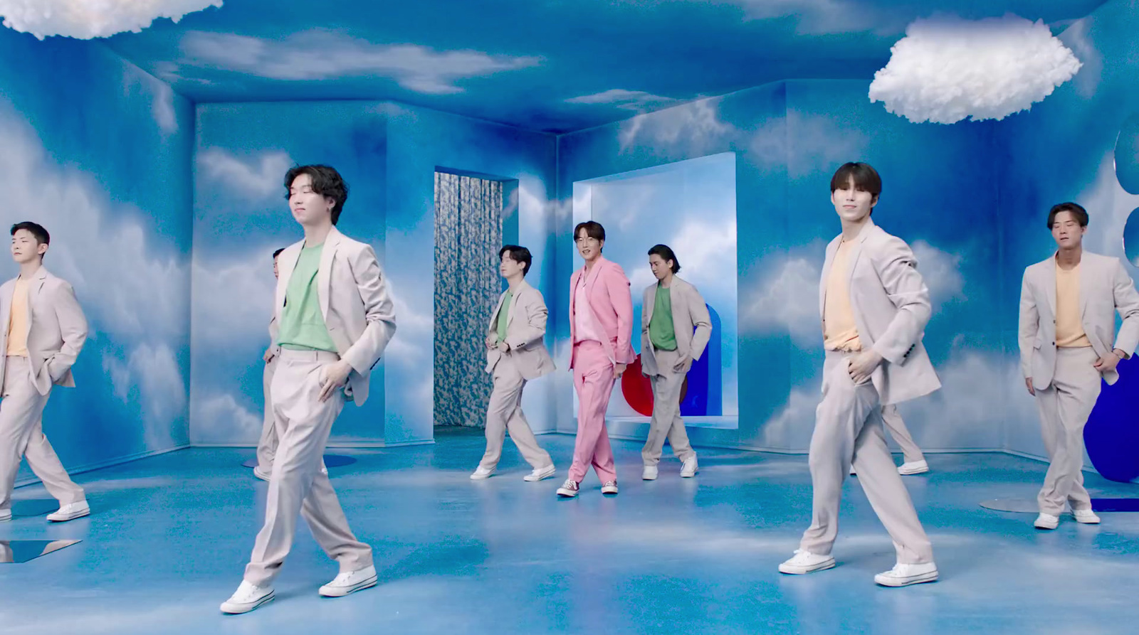 a group of men walking across a blue room