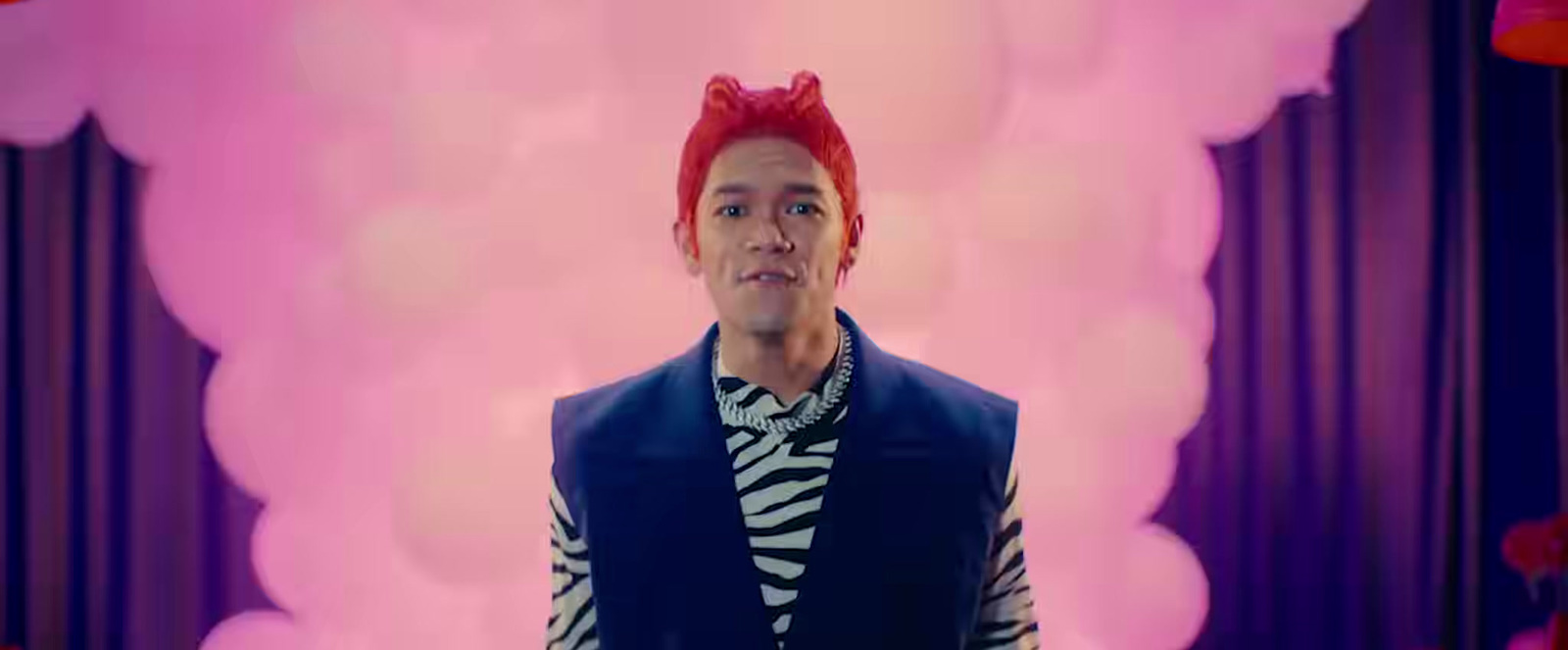 a man with red hair wearing a blue vest