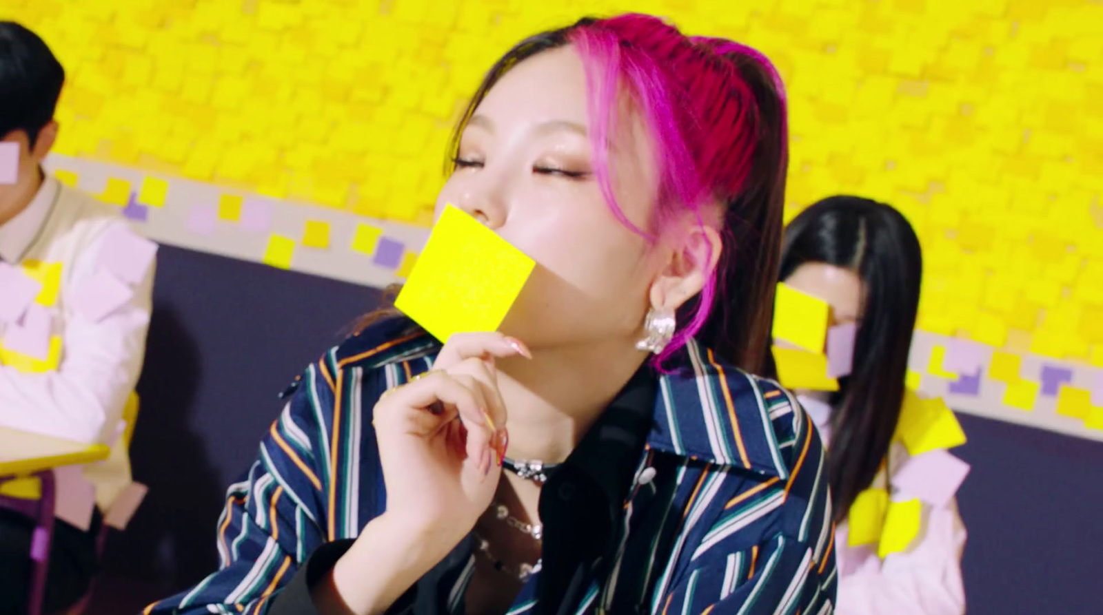 a woman with pink hair is eating a piece of paper