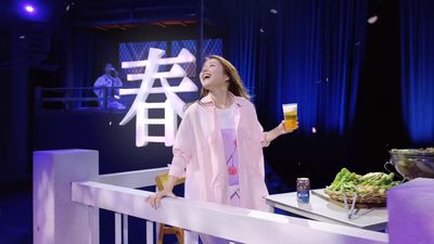 a woman standing on a stage holding a glass of beer