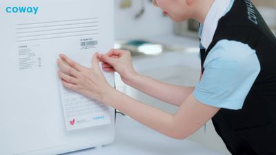 a woman in a black and blue shirt working on a white refrigerator