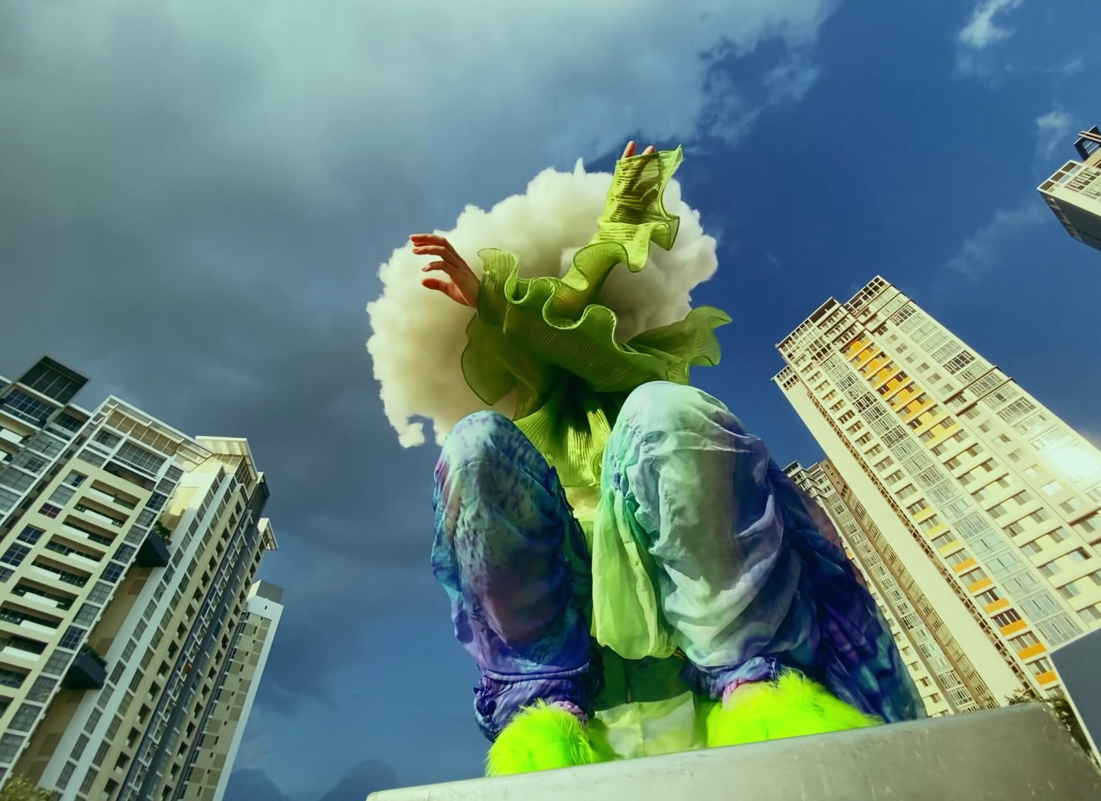 a person sitting on a ledge in front of tall buildings