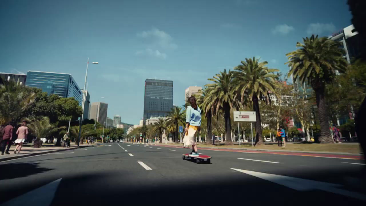 a man riding a skateboard down a street next to palm trees