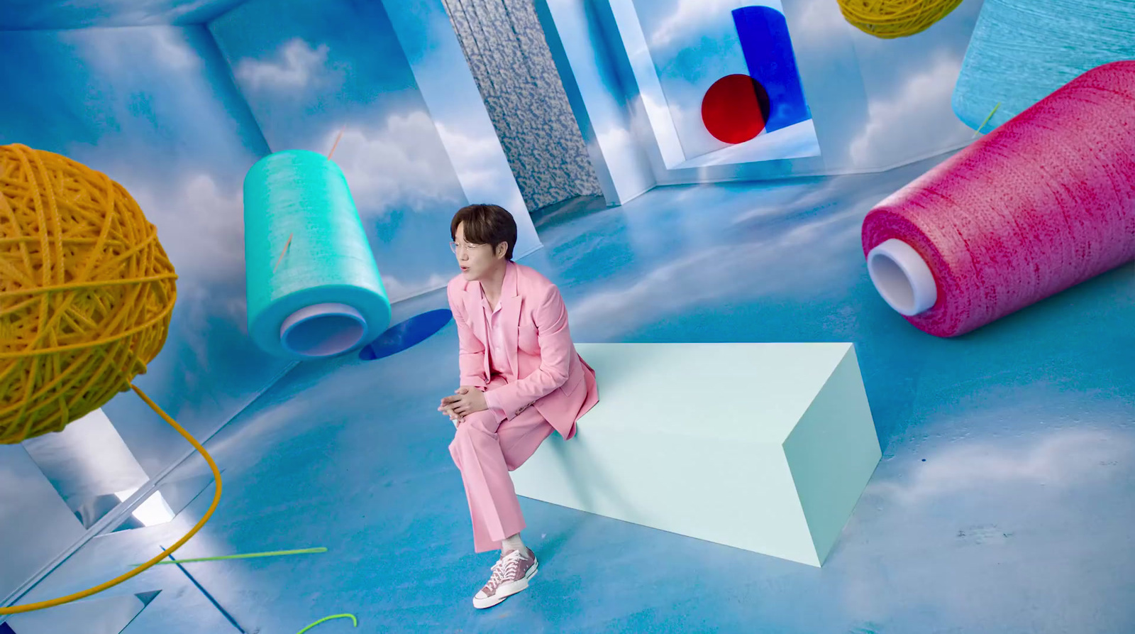 a woman in a pink suit sitting on a white box