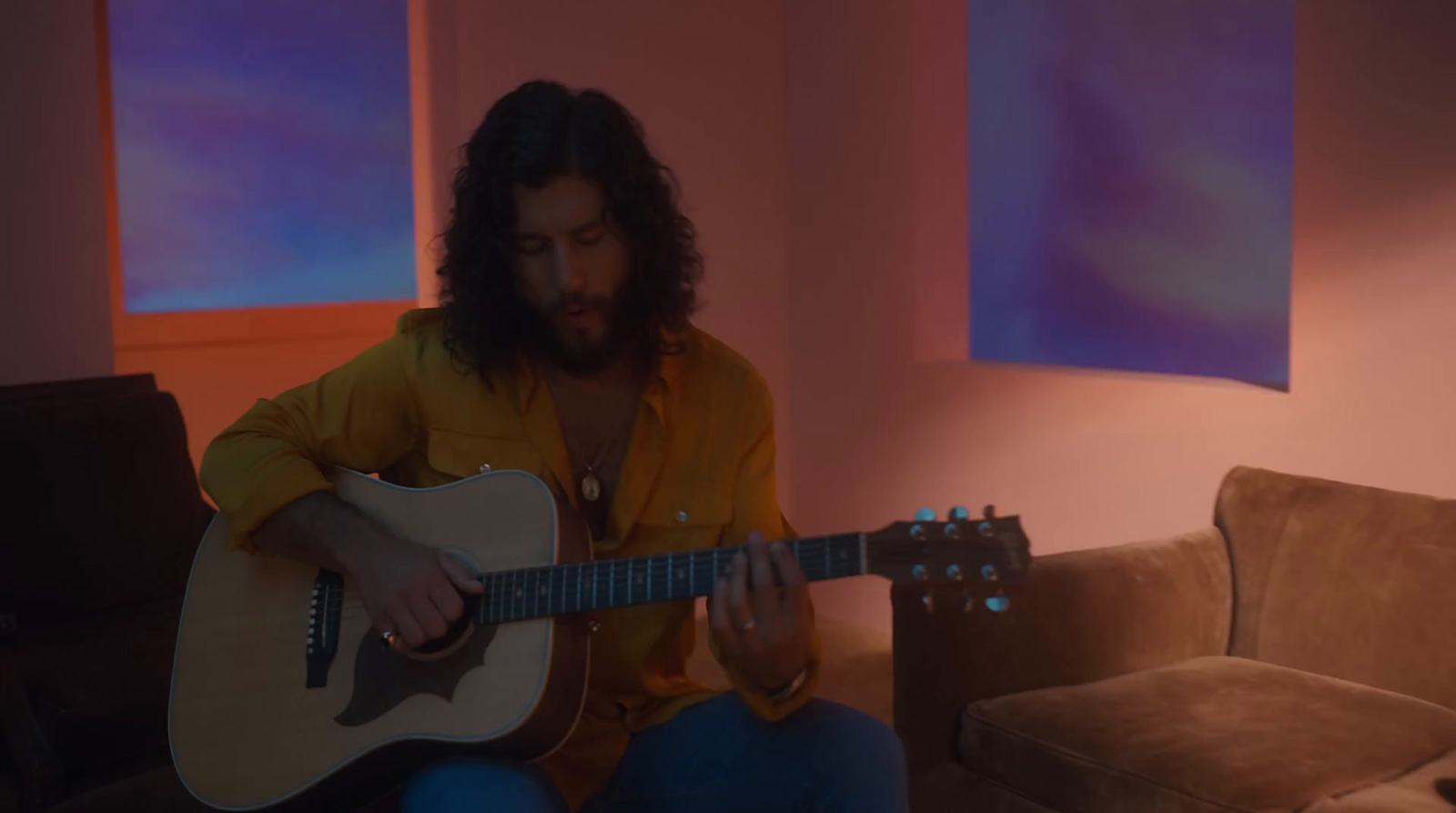 a man sitting on a couch playing a guitar