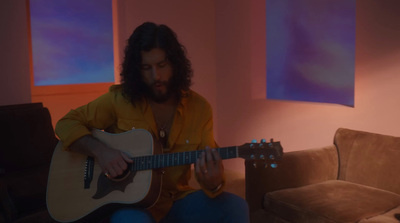 a man sitting on a couch playing a guitar