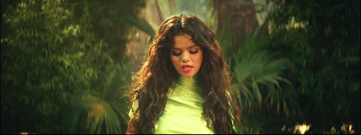 a woman with long brown hair standing in a forest