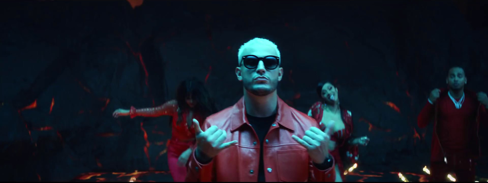 a man in a red jacket and sunglasses standing in front of a group of people