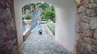 a person riding a scooter down a narrow street