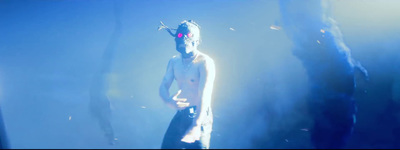 a shirtless man standing in front of a blue background