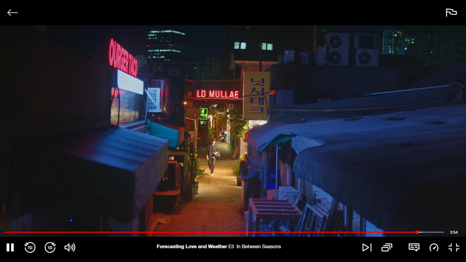 a narrow alley way with a neon sign in the distance