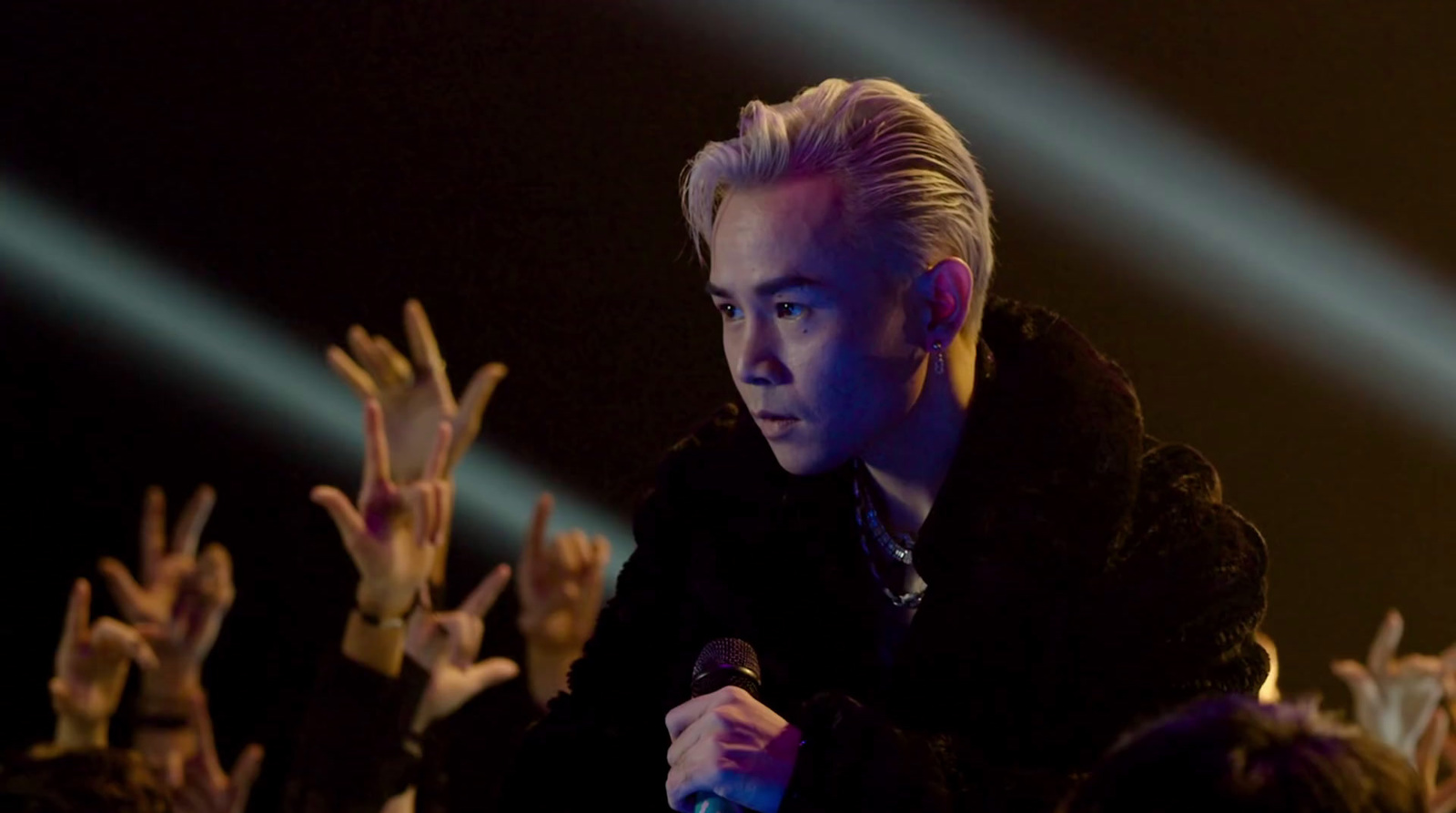 a man holding a microphone in front of a crowd of people