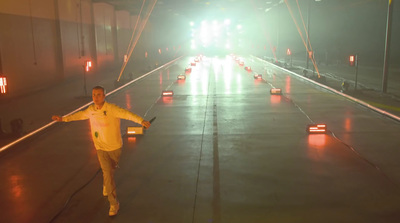 a man in a yellow jacket is running on a road