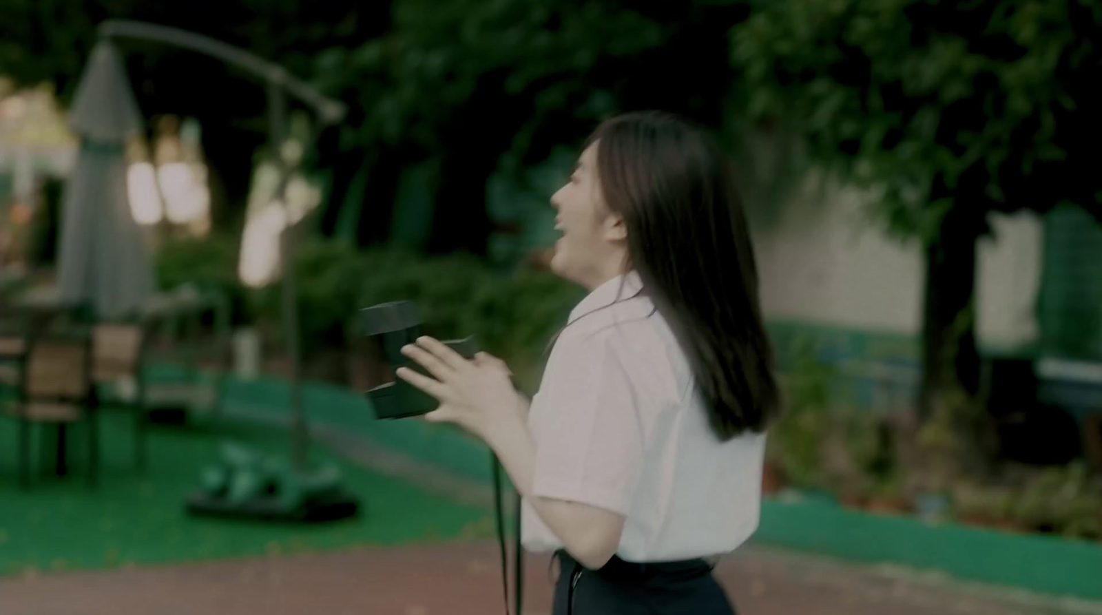 a woman standing in a park holding a hat