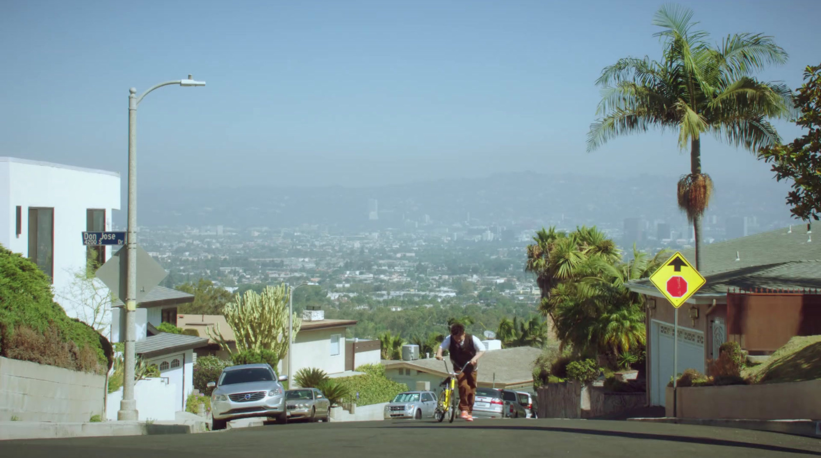 a man walking down a street next to palm trees