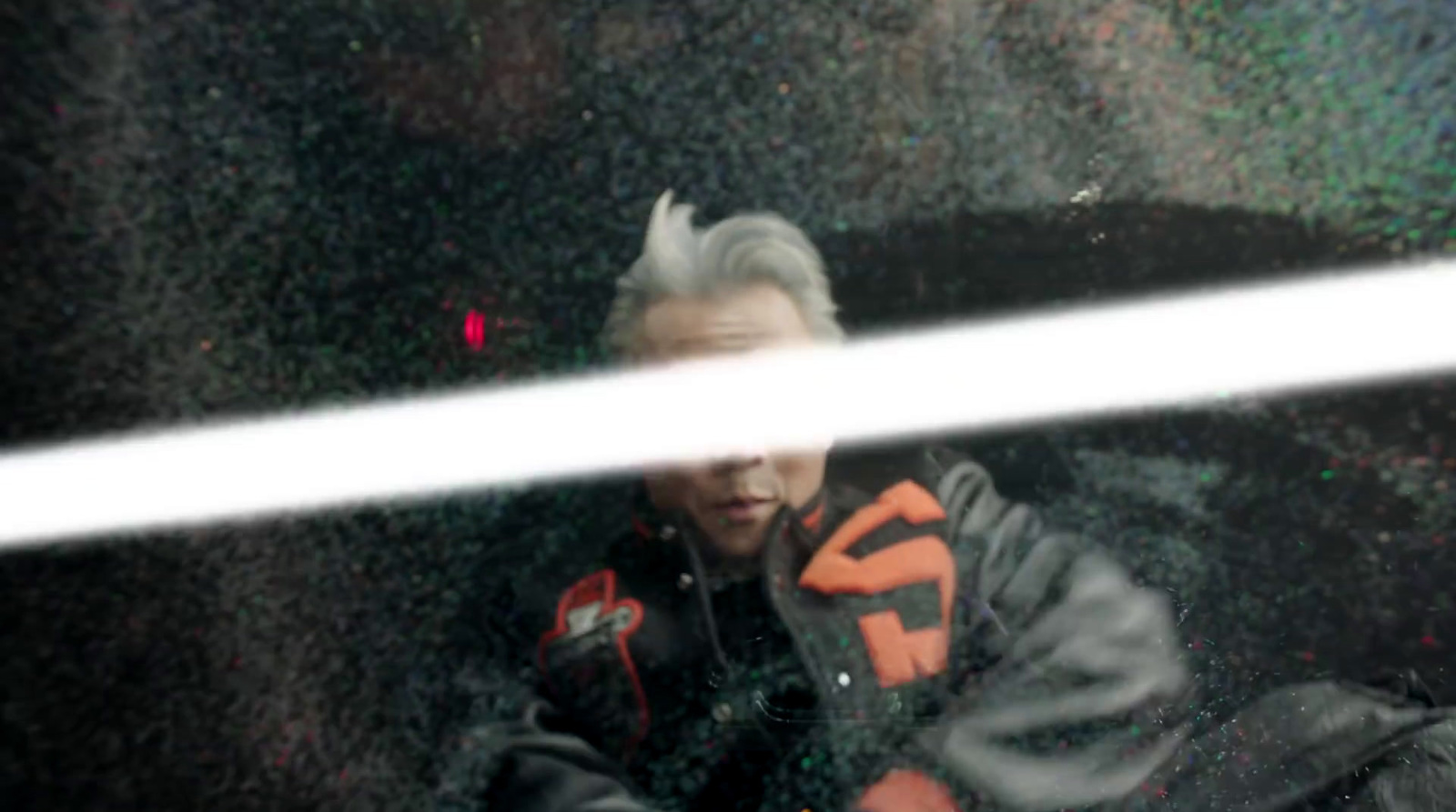 a man in a black and orange jacket looking out a window