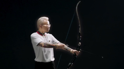 a man in a white shirt holding a bow and arrow