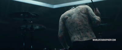 a man with tattoos on his back playing drums