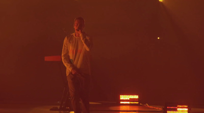 a man standing on a stage talking on a cell phone