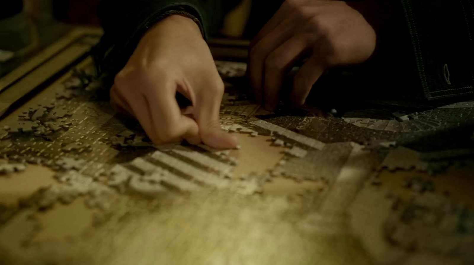 a person touching a piece of puzzle on a table