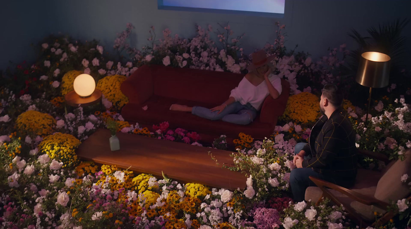 a couple of people sitting on a couch in a room filled with flowers