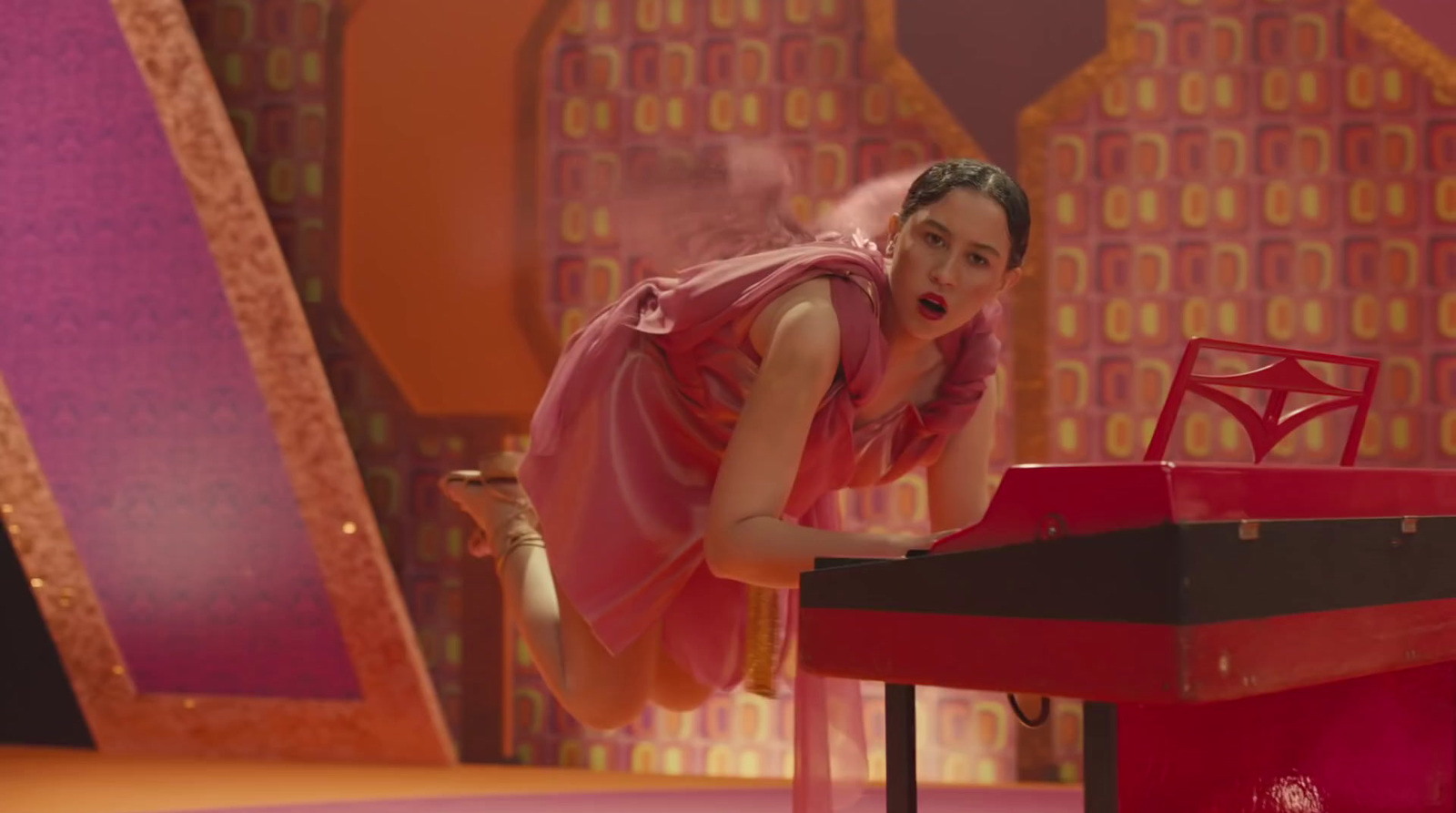 a woman in a pink dress leaning over a red table