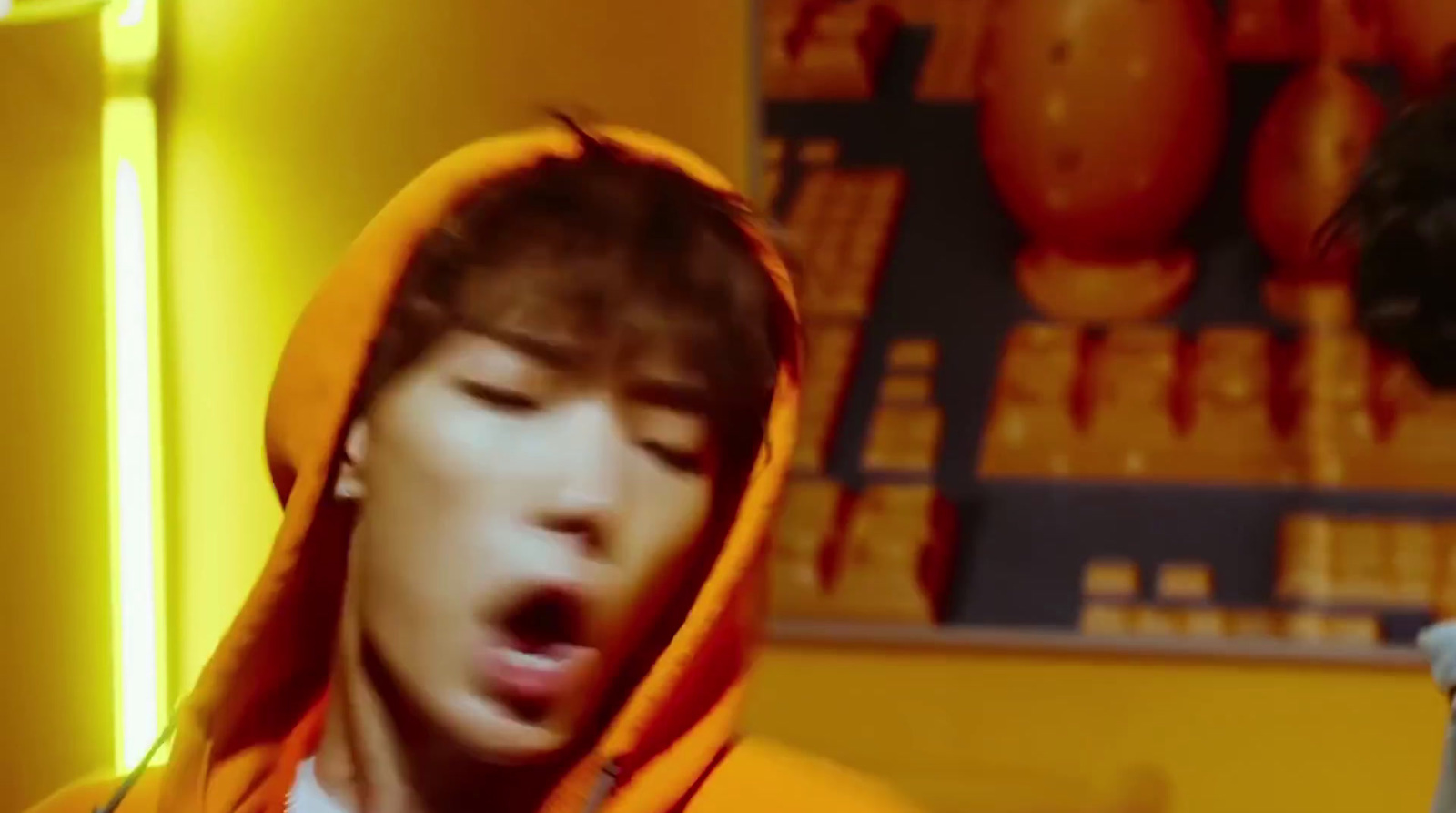 a young man in a yellow hoodie making a surprised face