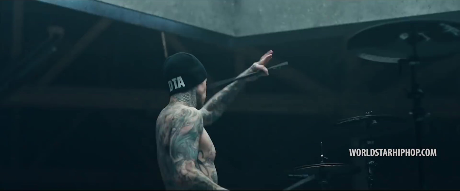 a man with a tattoo on his arm and a drum set in front of him