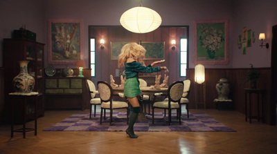 a woman in a green dress is dancing in a dining room