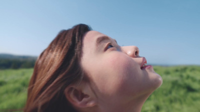 a woman looking up into the sky with a green field in the background