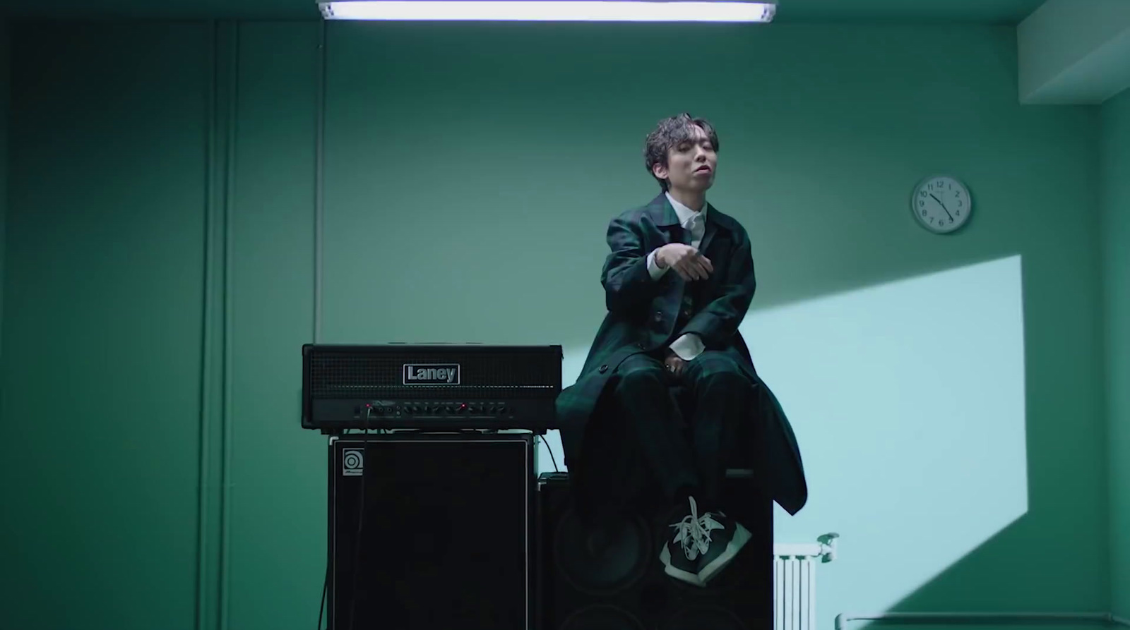 a man sitting on top of a amp in a room