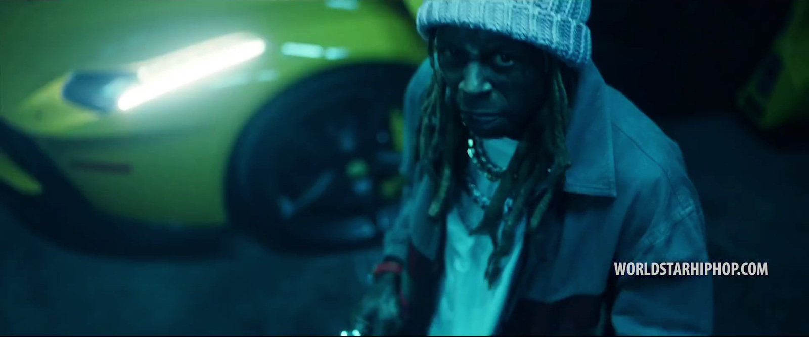 a man with dreadlocks standing next to a yellow car