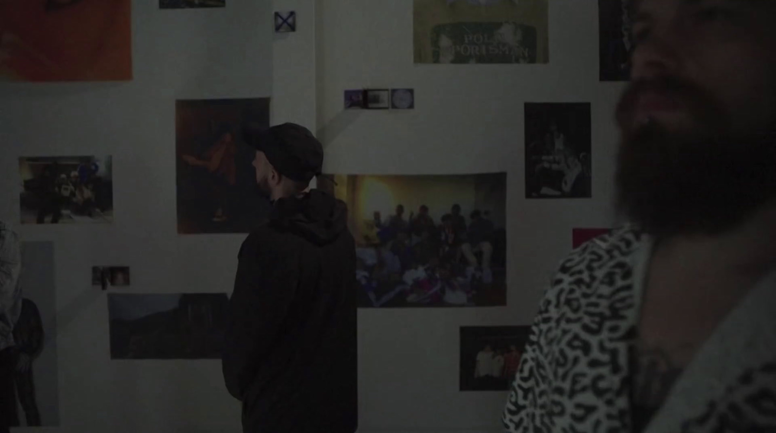 a man standing in front of a wall with pictures on it