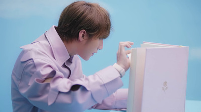 a man in a pink shirt leaning over a book