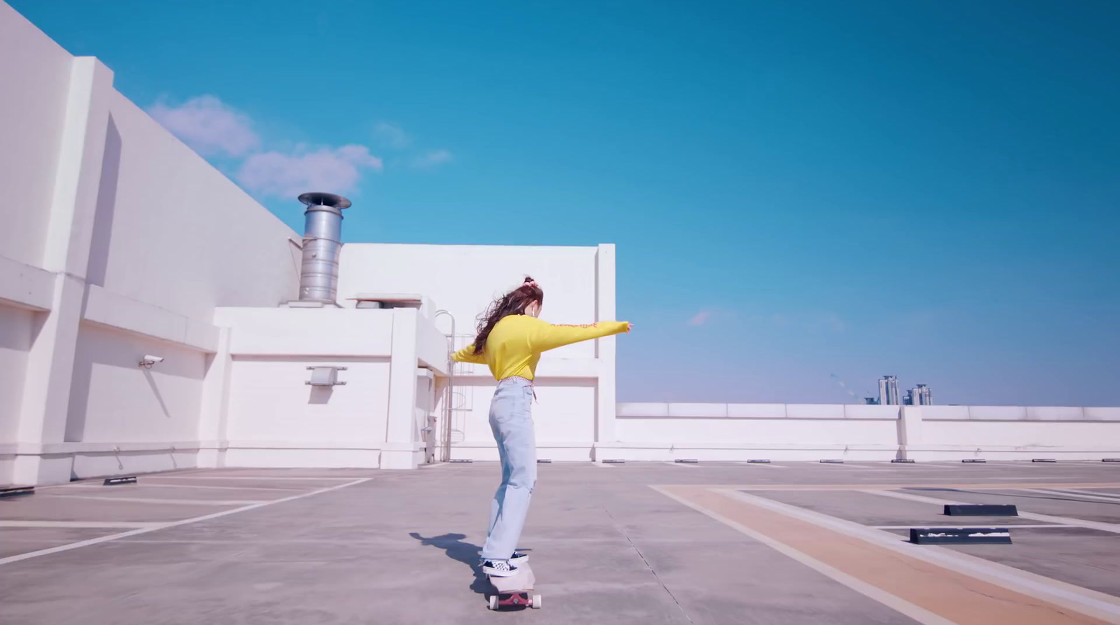 a woman riding a skateboard across a parking lot