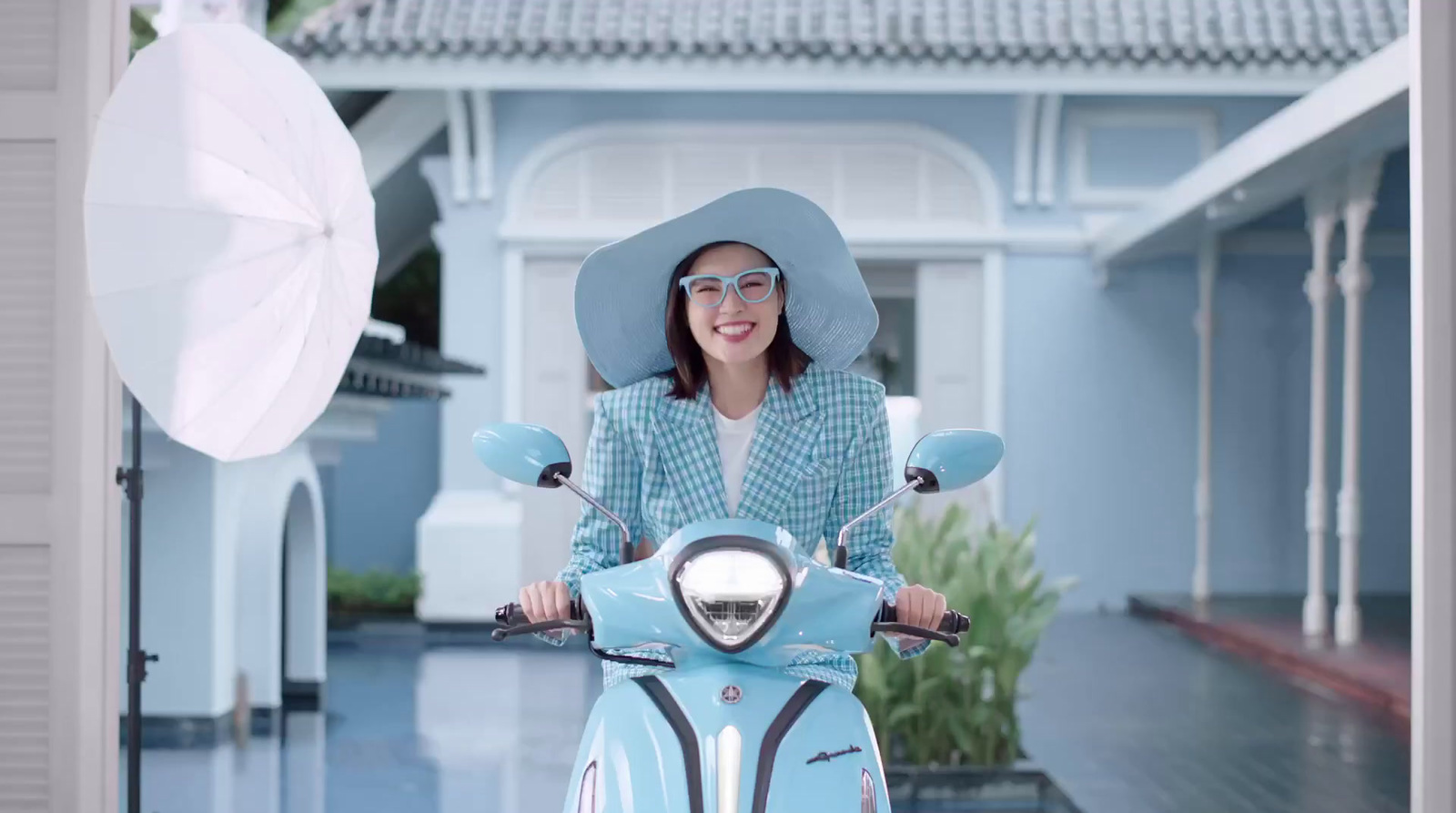 a woman wearing a hat and sunglasses on a scooter