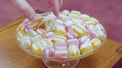 a person reaching for a candy bar in a glass bowl