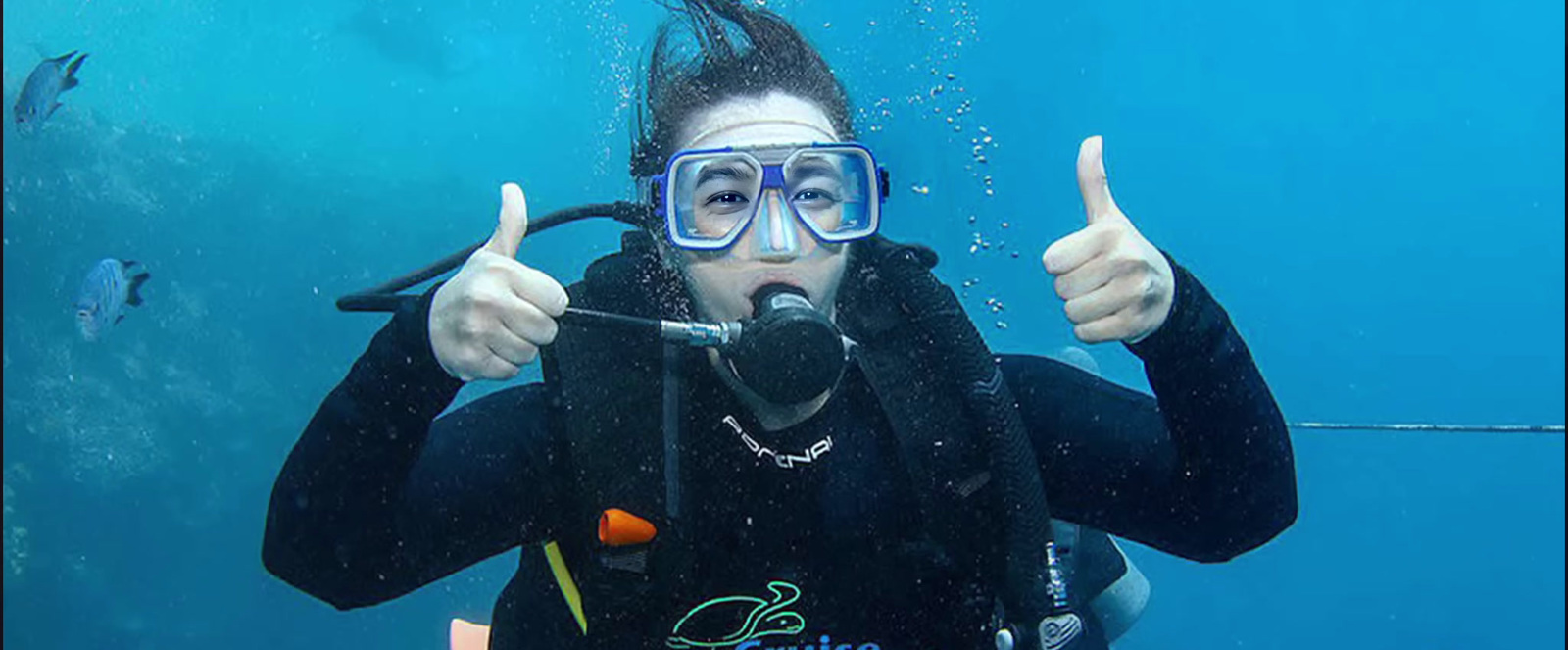 a woman in a scuba suit giving a thumbs up