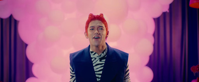 a man with red hair wearing a vest and striped shirt