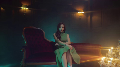 a woman in a green dress sitting on a red chair