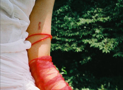 a woman in a white dress with a red ribbon on her arm