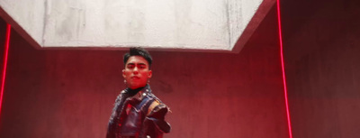 a man in a leather jacket standing in a red room