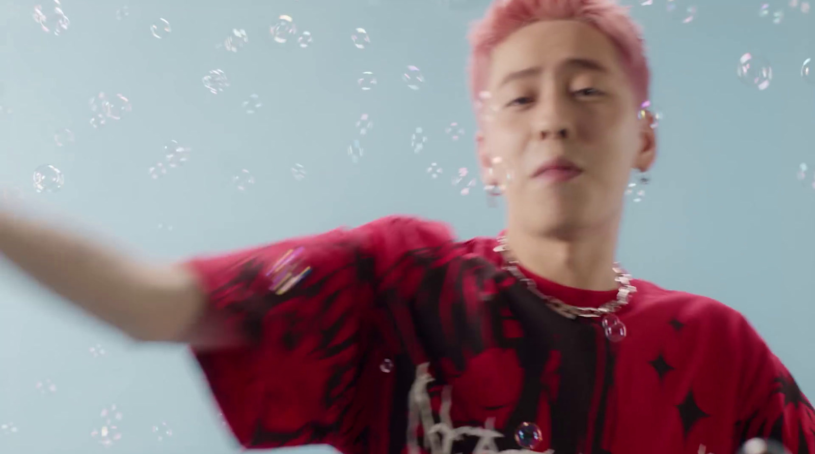 a man with pink hair is blowing bubbles